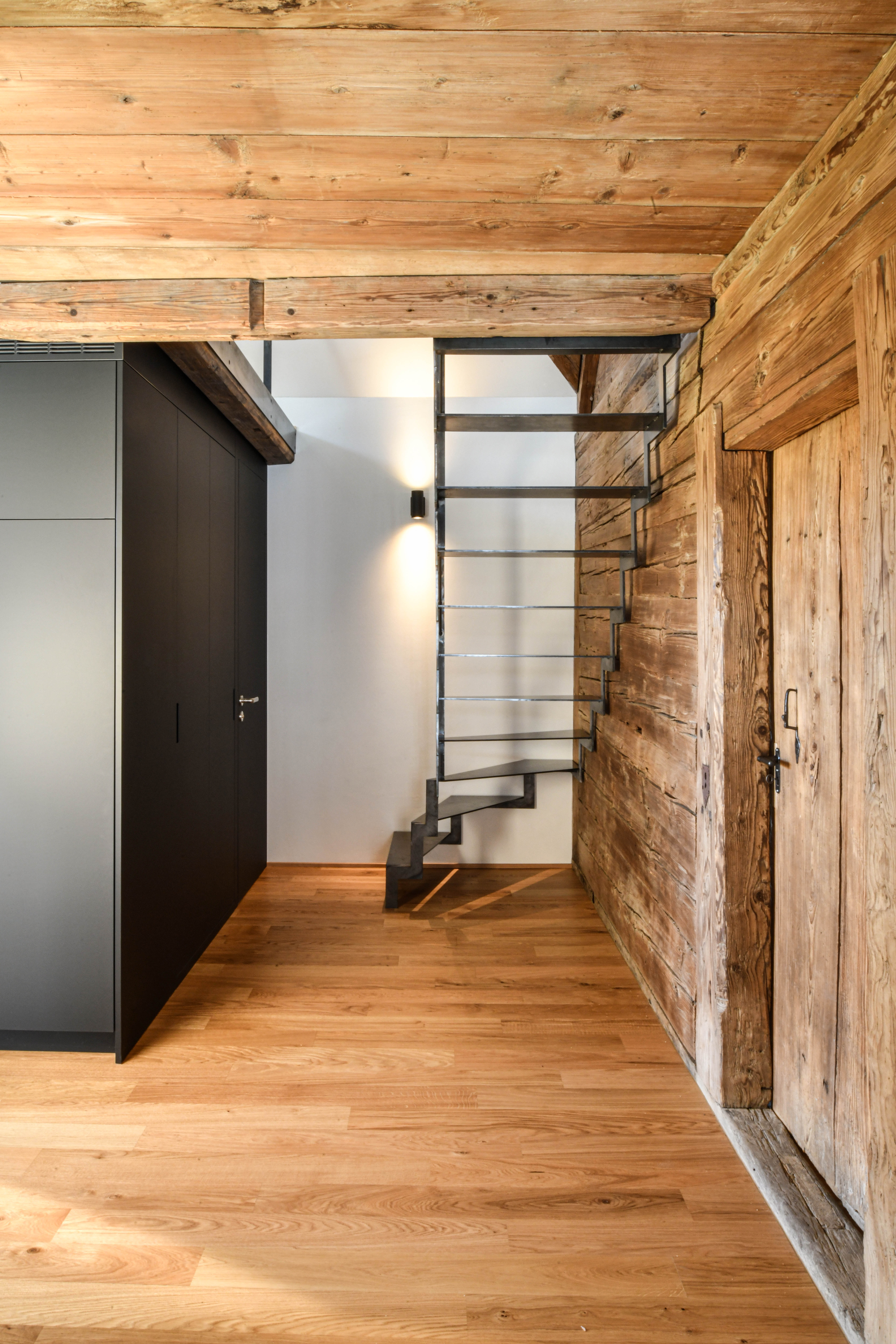 Wohnung im Hochparterre nach dem Umbau mit Holztüre rechts, Treppe in der Mitte und schwarzem Schrank links